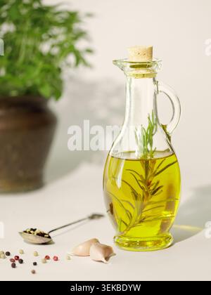 Glasflasche mit Rosmarin infundiertem Olivenöl mit Knoblauch und Pfeffer Stockfoto