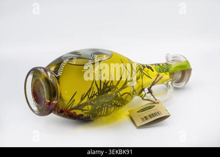 Kiew, Ukraine - 11. April 2024: Dekorative Glaskaraffe aus Olio di Oliva extra nativem Olivenöl, angereichert mit frischen Rosmarinzweigen und Gewürzen, editori Stockfoto