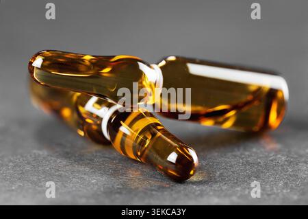 Makroaufnahme gekreuzter brauner Arzneimittelröhrchen mit geringer Schärfentiefe auf dunkelgrau Stockfoto
