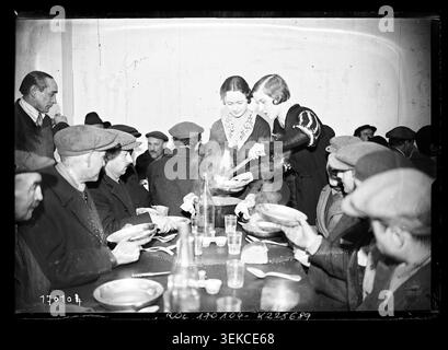 Agence Rol produzierte 1933 ein Pressefoto von Studenten, die Arbeitslosen in der Rue Cujas 15 im fünften Arrondissement von Paris Mahlzeiten servierten. Die Szene zeichnet karitative Arbeit und Suppenküche im Quartier Latin während einer Zeit der sozialen Entlastung auf. Stockfoto