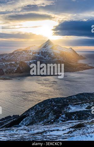 Eine dramatische vertikale Hochwinkellandschaft, in der ein scharfer, majestätischer Berggipfel während eines spektakulären Winteruntergangs im Lofo festgehalten wird Stockfoto