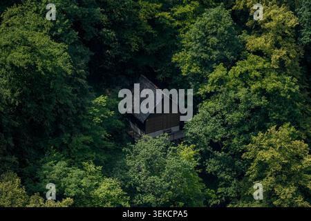 Kleine rustikale Hütte, umgeben von dicken Baumkronen, repräsentiert Privatsphäre, Wald Rückzugsort, Natur Zuflucht und abgelegenes Wohnen. Stockfoto