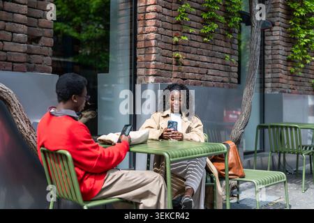 afroamerikanisches stilvolles Paar Freunde Mann und Frau, die sich auf der Open Air Café Terrasse in der Innenstadt entspannen Stockfoto