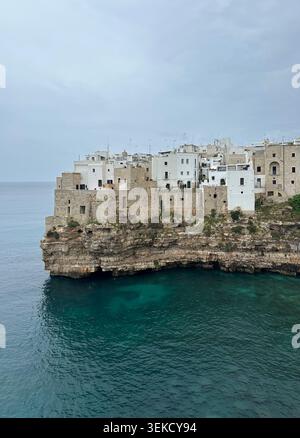Weiße Gebäude befinden sich auf einer felsigen Klippe in Polignano a Mare, Apulien, Italien. Die Gebäude sind eng aneinander geschachtelt, mit Blick auf die Adria W Stockfoto