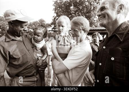 Jimmy Carter hält seine Tochter Amy, als er den Senator und ehemaligen Astronauten John Glenn seinem Pächter Leonard Wright und seiner Tochter vorstellt. Stockfoto