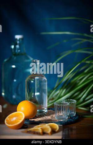 Glas-Mezcal-Flaschen mit Orangen und Shot-Gläsern Stockfoto