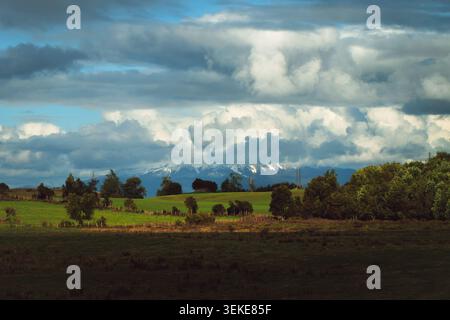 Panoramafoto mit Weitwinkelaufnahmen, die eine dramatische und atmosphärische ländliche Szene im Süden Chiles mit dem schneebedeckten Gipfel von Calbuc aufnehmen Stockfoto