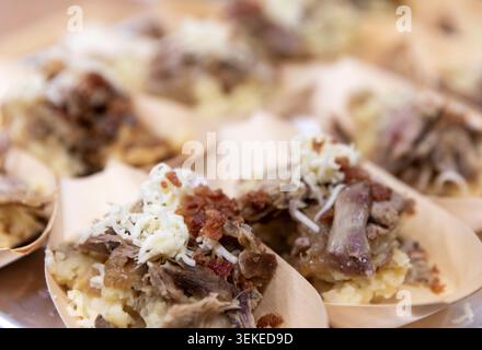 Vorspeise aus Pulled Pork, serviert in einzelnen Holzlöffeln mit Kartoffelpüree, Speckstückchen, Käse und herzhaften Zwiebeln auf einer Veranstaltung mit Catering Stockfoto