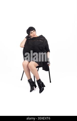 Eine durchdachte, große Frau, die auf einem Stuhl sitzt und nach unten blickt Stockfoto
