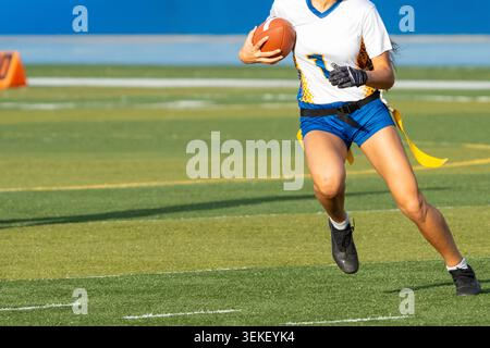 Nicht wiedererkennbare Fahnenfußballspielerin fährt über das Feld, während sie den Ball während eines Spiels im Freien trägt. Stockfoto