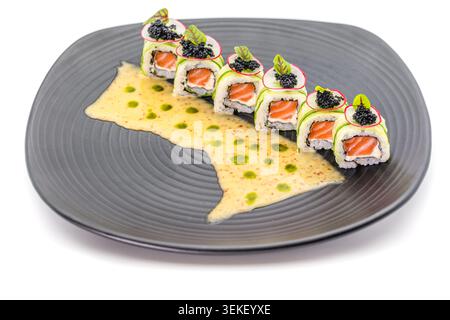 Elegante Sushi-Brötchen mit schwarzem Kaviar und cremiger Sauce auf dunklem Gourmet-Teller isoliert auf weißem Hintergrund Stockfoto