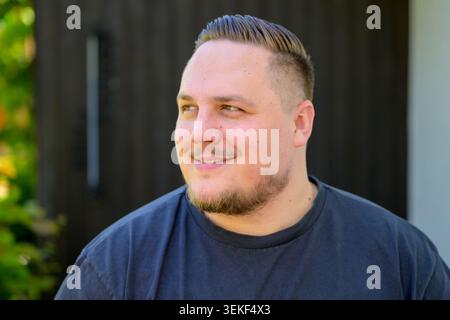 Porträt eines entspannten jungen Mannes, der natürlich lächelt, während er seitwärts schaut. Authentisches Lifestyle-Bild, das Positivität, Zuversicht, Optimismus und Kal repräsentiert Stockfoto