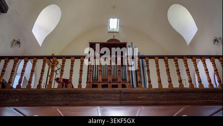 Holzbalkon mit kunstvollen Geländern in einer Kirche. Orgelpfeifen hinter dem Geländer sichtbar Stockfoto