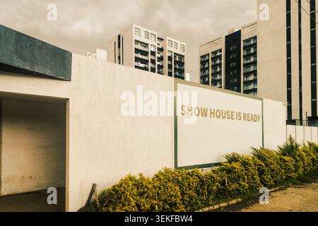 Eine moderne Wohnsiedlung mit „Show House is Ready“-Schild unter Moody Sky Stockfoto