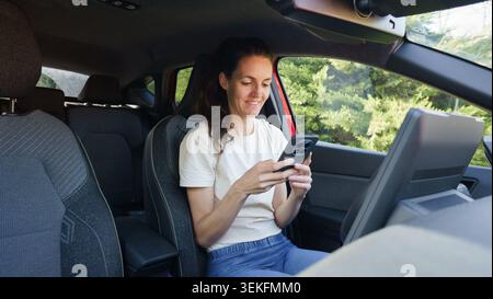 Frau, die ein Smartphone in einem Auto benutzt Stockfoto