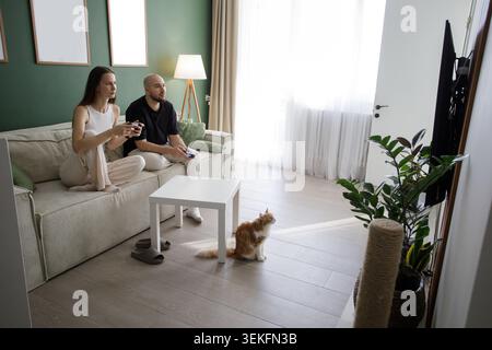 Attraktives Paar, das zu Hause Konsolenspiel spielt. Aufregendes Videospiel für aktive Paare Stockfoto