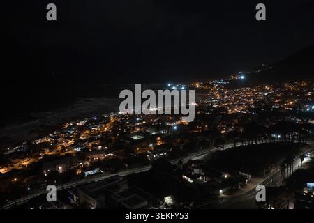 Nächtlicher Luftblick auf Kapstadts Camps Bay Coast mit gewundenen Straßen Stockfoto
