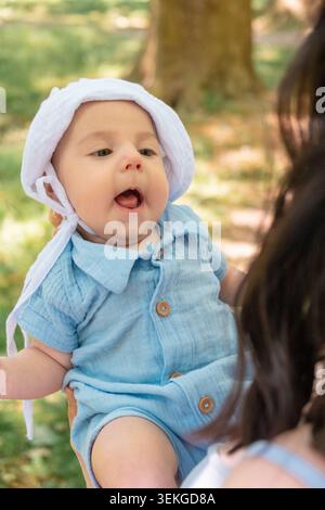 Süßes Baby im blauen Outfit draußen mit Eltern Stockfoto