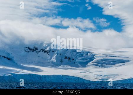 Eine beschauliche antarktische Landschaft in der Nähe des Hafens Mikkelsen auf Trinity Island, mit starken Reflexen, zerklüfteten Bergen und beeindruckenden Eisbergen Stockfoto