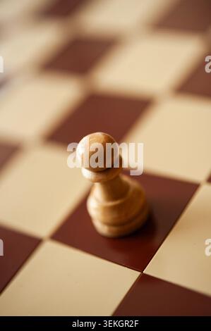 Hölzerne Schachfigur allein auf Schachbrett, warmes Licht und flacher Fokus, minimalistisches Strategiekonzept Stockfoto