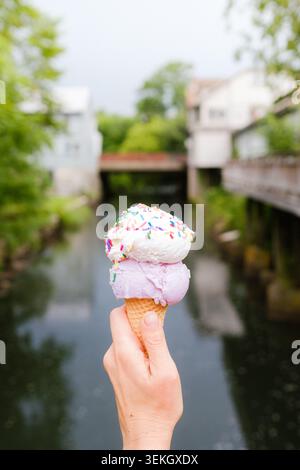 Eine Frauenhand, die im Sommer am Fluss in West Stockbridge in den Berkshires, Massachusetts, USA, ein Eis mit Streuseln hält. Stockfoto