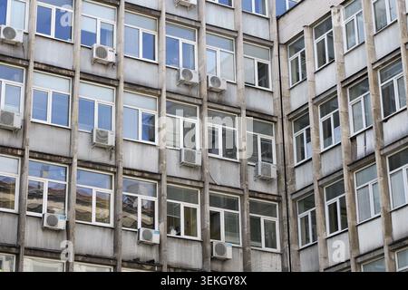 Moderne Architektur eines Bürogebäudes mit zahlreichen Fenstern mit unterschiedlichen Rahmen und mehreren Klimaanlagen, die auf dem installiert sind Stockfoto