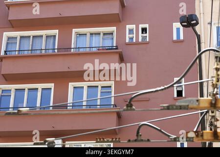 Fassade des Apartmentgebäudes mit mehreren Fenstern und Balkonen, mit verschiedenen Straßenelementen wie Straßenlaterne und elektrischem wlan Stockfoto
