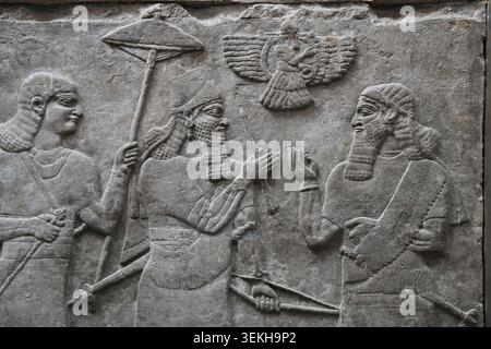 Assyrisch, 9. Jh. v. Chr. Irak, Nimrud, Nordwestpalast. Panel 7. Saal B. Ashurnasirpal II. Steht mit Sonnenschirm und hält die erhabenen Pfeile symbolisch für den Sieg, begleitet vom Gott in der geflügelten Scheibe und hoher Beamter. British Museum. London. Stockfoto