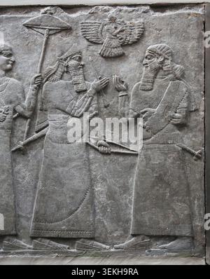 Assyrisch, 9. Jh. v. Chr. Irak, Nimrud, Nordwestpalast. Panel 7. Saal B. Ashurnasirpal II. Steht mit Sonnenschirm und hält die erhabenen Pfeile symbolisch für den Sieg, begleitet vom Gott in der geflügelten Scheibe und hoher Beamter. British Museum. London. Stockfoto