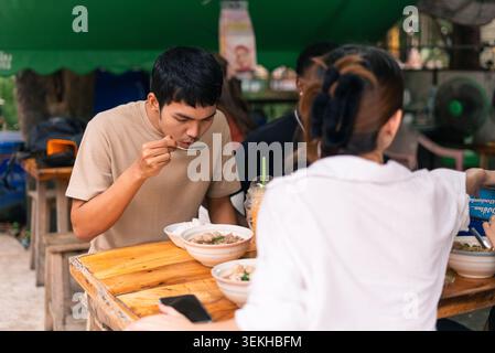Asiatischer Mann, der traditionelles Street Food am Restaurantstand im Freien genießt Stockfoto