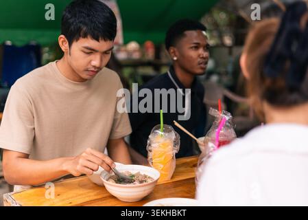 Junge Menschen genießen Streetfood und Getränke an einem Marktstand im Freien Stockfoto