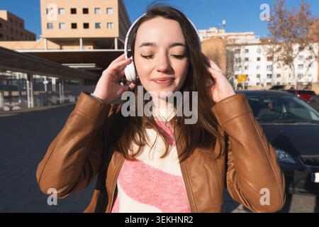 Junge Frau schließt die Augen und hört Musik im Freien mit kabellosen Kopfhörern Stockfoto