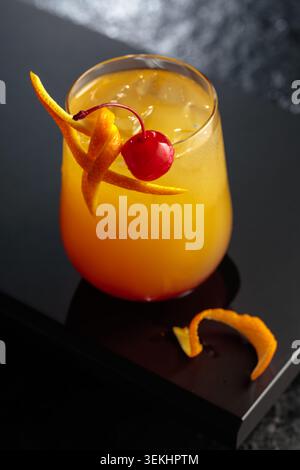 Cocktail Tequila Sonnenaufgang mit Orangensaft, silbernem Tequila, Grenadine und Eis. Cocktail garniert mit Maraschino-Kirsche und Orangenschale. Stockfoto