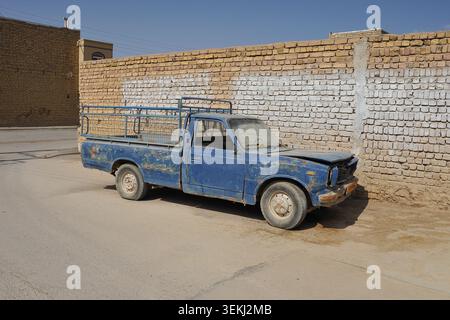 Der alte blaue Pickup-Truck parkt bei Brick Wall im ländlichen Iran Stockfoto