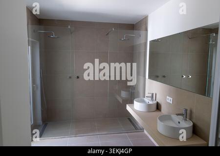 Geräumiges, modernes Badezimmer mit großem Duschbereich mit Glasdusche und zwei Duschköpfen sowie einem Kosmetikbereich mit zwei Waschbecken und Spiegeln Stockfoto