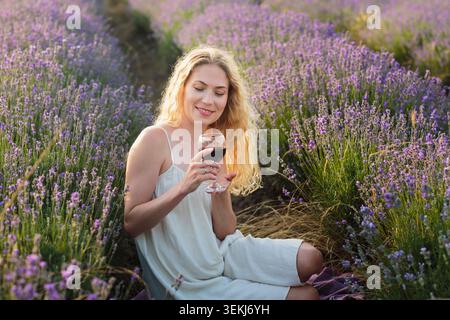 Lächelnde Frau genießt Rotwein im Lavender Field Stockfoto