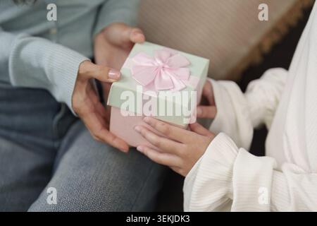 Eine Mutter, die eine wunderschön verpackte Geschenkbox von ihrer Tochter erhält, um die Freude und Liebe am Muttertag zu feiern Stockfoto