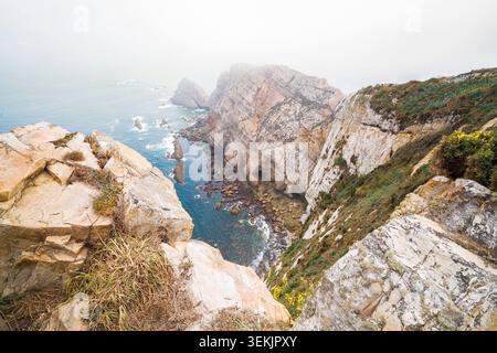 Zerklüftete Küstenklippen und Meeresstapel zeigen die mächtige Schönheit der Natur entlang des Atlantischen Ozeans, während der Horizont in die nebelige Atmosphäre verschwindet Stockfoto