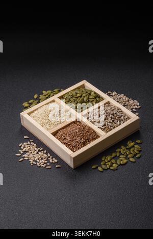 Eine Schachtel mit Flachs, Kürbis, Sonnenblumen und Sesamsamen, Zutaten für eine gesunde Ernährung. Flachs-, Sesam-, Kürbis- und Sonnenblumenkerne als Lebensmittelhintergrund f Stockfoto