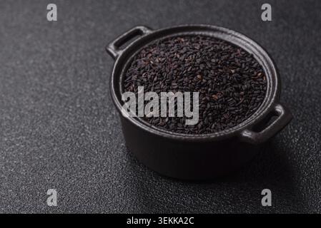 Schwarze Sesamsamen in einer Schüssel, eine Zutat für Öl und gesunde Ernährung. Schwarzer Sesam als Essenshintergrund für dein Design Stockfoto