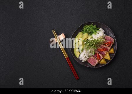 Gebratene Thunfisch-Tataki in einer Schüssel mit Sesamsamen, Reis und Gemüse. Thunfisch Tataki als Hintergrund für Ihr Design Stockfoto