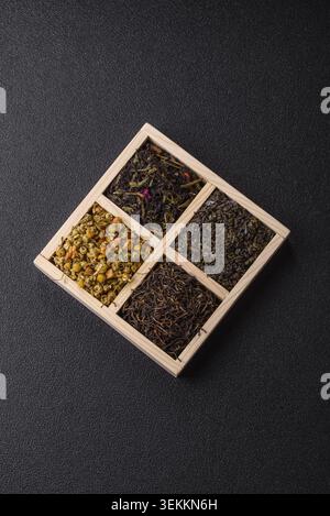 Eine Holzkiste mit verschiedenen Arten von getrocknetem Tee, grünem, schwarzem, Obst und Kamille. Trockener Tee in der Box als Hintergrund für Ihr Design Stockfoto