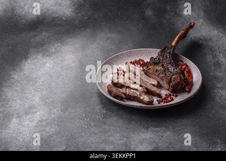 Gegrilltes Fleisch mit Knochen, Rindfleisch-Tomahawk-Steak, saftiges gegrilltes Fleisch. Tomahawk Steak als kulinarischer Hintergrund für Ihr Design Stockfoto