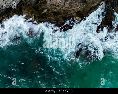 Mächtige Meereswellen krachen gegen zerklüftete Felsformationen und erzeugen Schaum und spritzendes Wasser im türkisfarbenen andamanenmeer in der Nähe von phuket thailand. Stockfoto