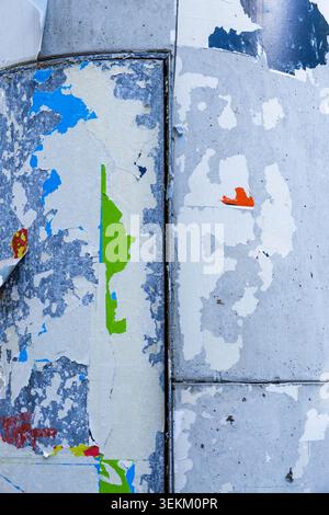Nahaufnahme von verwitterten Plakatresten und abblätternder Farbe auf einer städtischen Werbesäule. Distressed-Oberfläche mit mehrschichtigen Papierstrukturen, Schmirgeldetails. Stockfoto