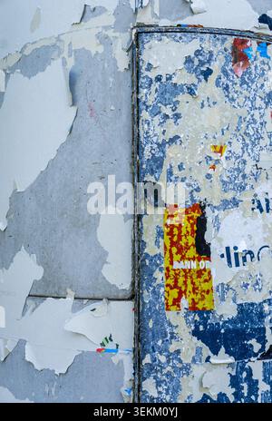 Nahaufnahme von verwitterten Plakatresten und abblätternder Farbe auf einer städtischen Werbesäule. Distressed-Oberfläche mit mehrschichtigen Papierstrukturen, Schmirgeldetails. Stockfoto