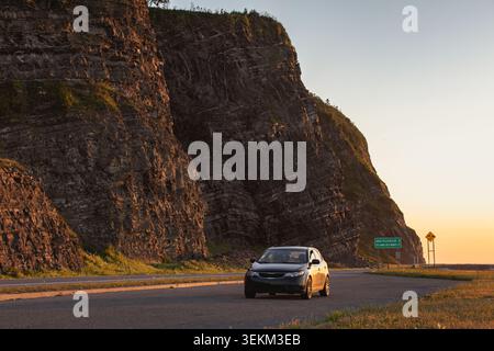 Blick auf ein schwarzes Auto, das im Sommer bei Sonnenuntergang an einer felsigen Klippe parkt Stockfoto