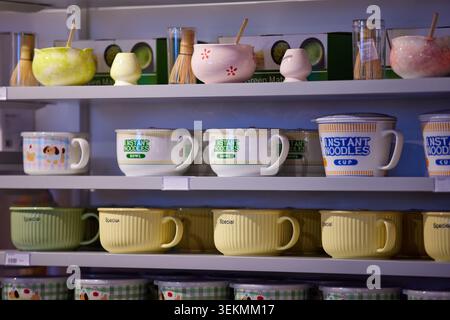 Regale mit Matcha-Teesorten, Bambus-Whiskys, Keramikschalen und Instant-Nudeltassen. Stockfoto