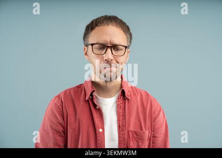 Verärgerter, nachdenklicher Mann schaut traurig nach unten beißende Lippen mit Aufregung runzelnde Stirn mit Brille isolierten Hintergrund. Stress Nervus Middle ag Stockfoto