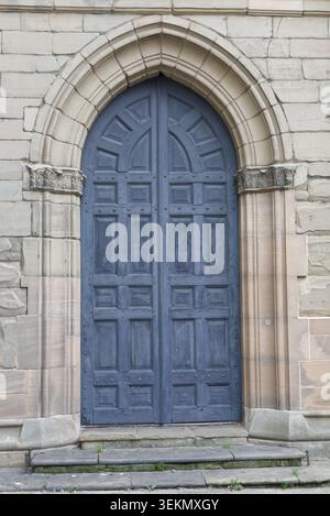 Große blau/graue hölzerne Kirchentür in Stein Stockfoto